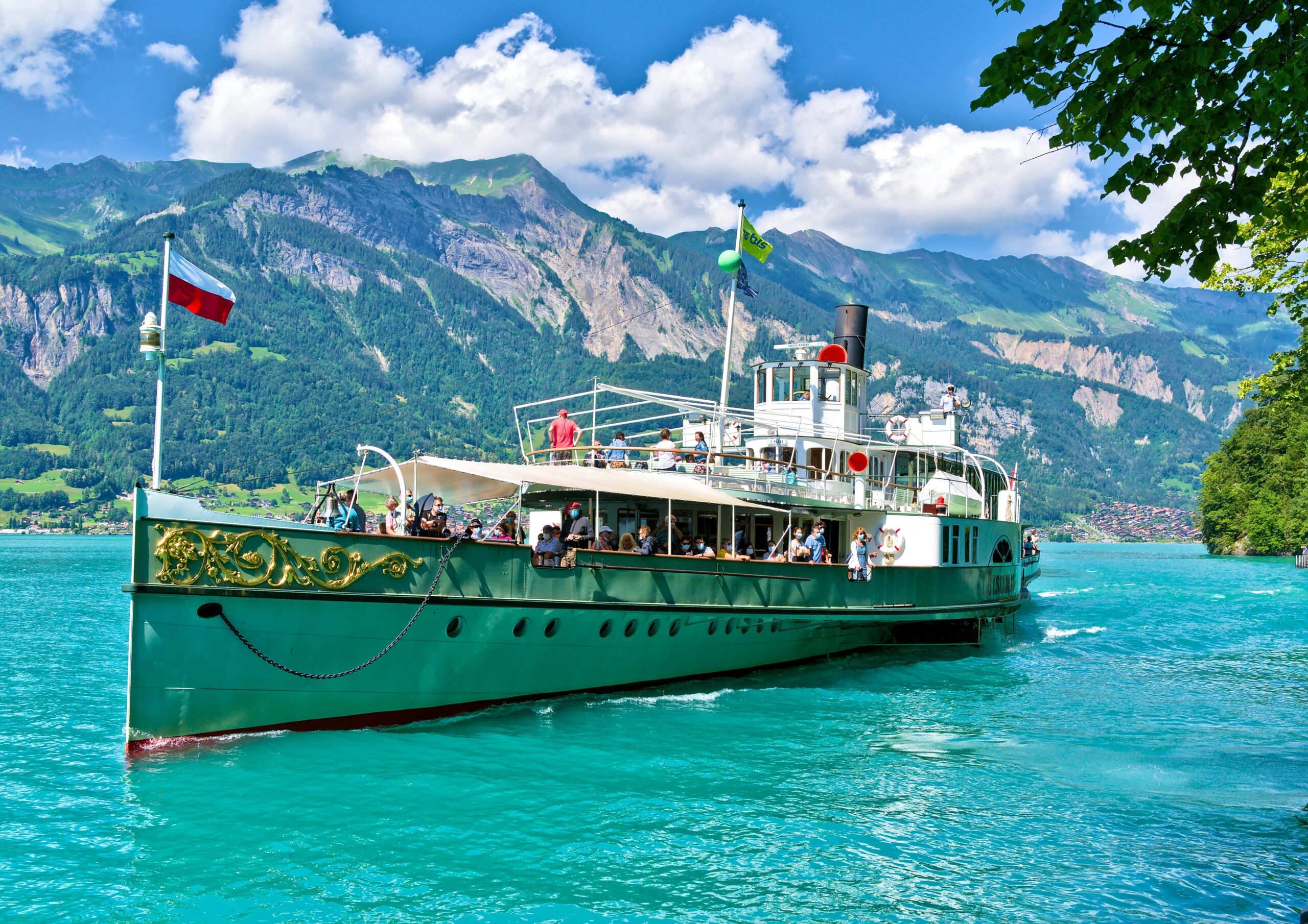 A cruise ship sails on turquoise Lake Brienz with mountains in the background.